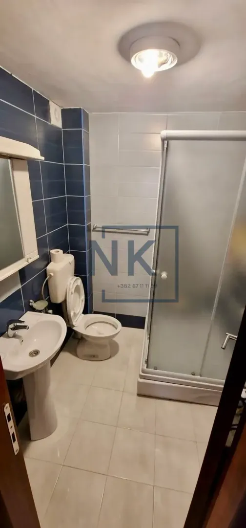 Kupatilo opremljeno umivaonikom, WC šoljom i tuš kabinom.