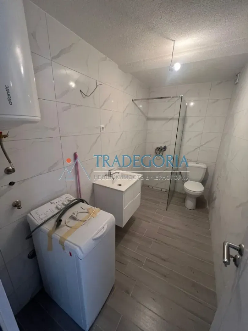 Renovirano kupatilo sa tuš kabinom, umivaonikom, WC šoljom i mašinom za veš.