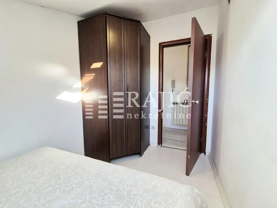 Smaller bedroom with a double bed, wardrobe, and an open door leading to the hallway.