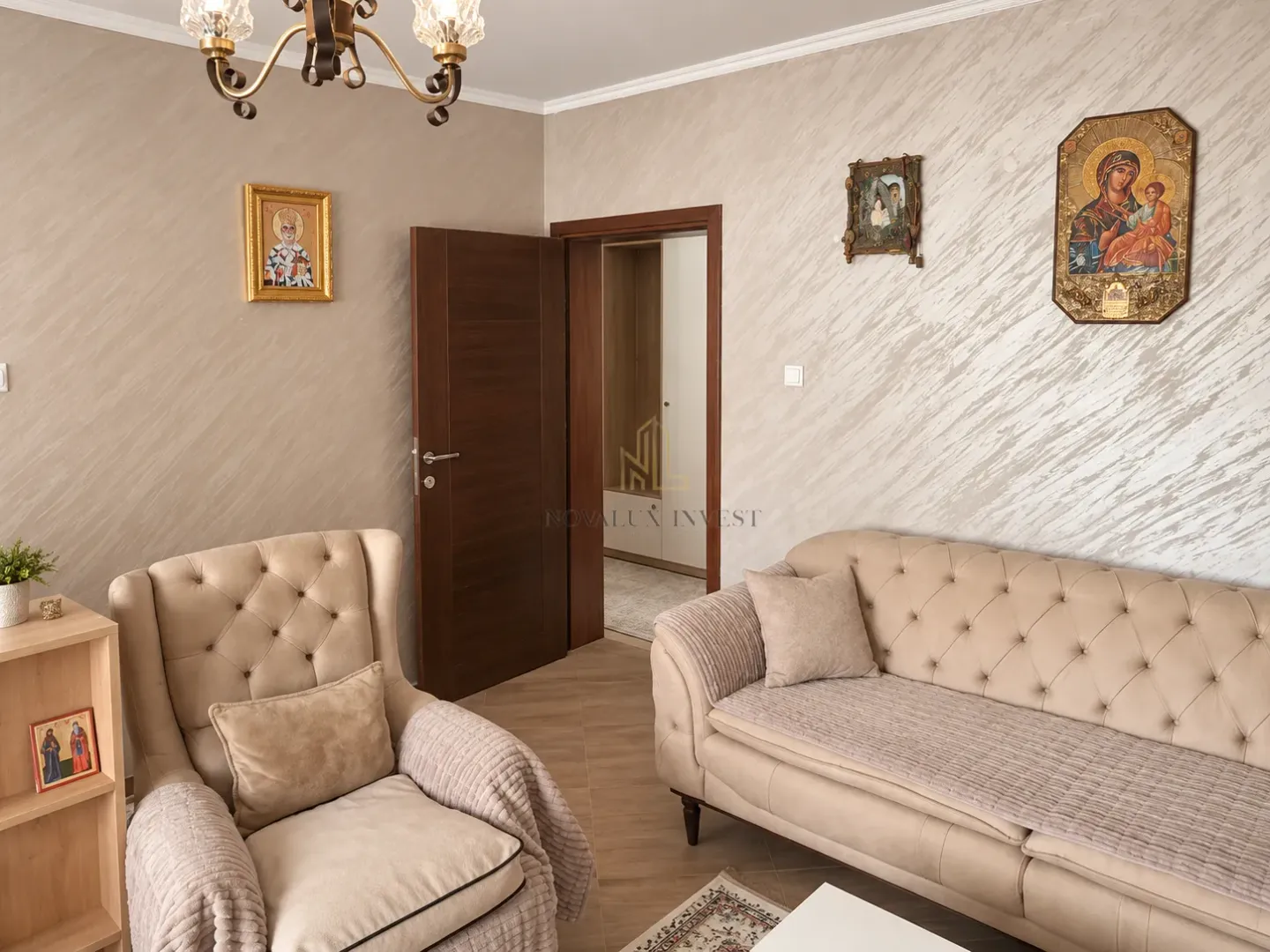 Dnevna soba sa bež garniturom, foteljom i dekorativnim elementima na zidu.
