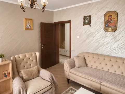 Dnevna soba sa bež garniturom, foteljom i dekorativnim elementima na zidu. - image 2