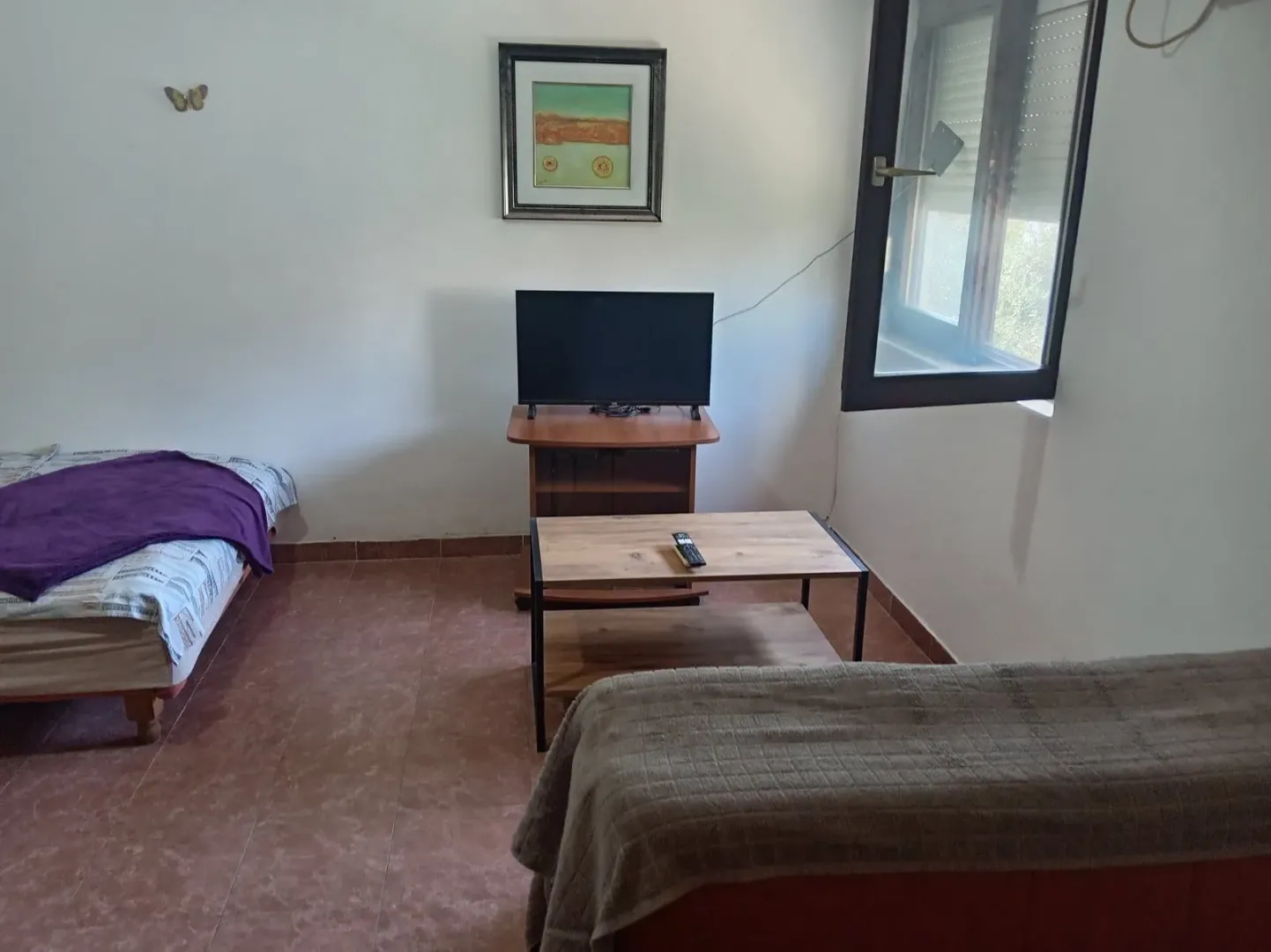 Small bedroom with a bed, television, and window.