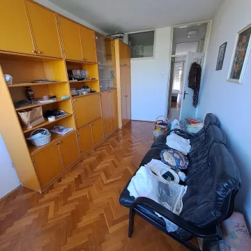 Dnevna soba sa velikim drvenim ormarom i crnim kaučem. - image 5