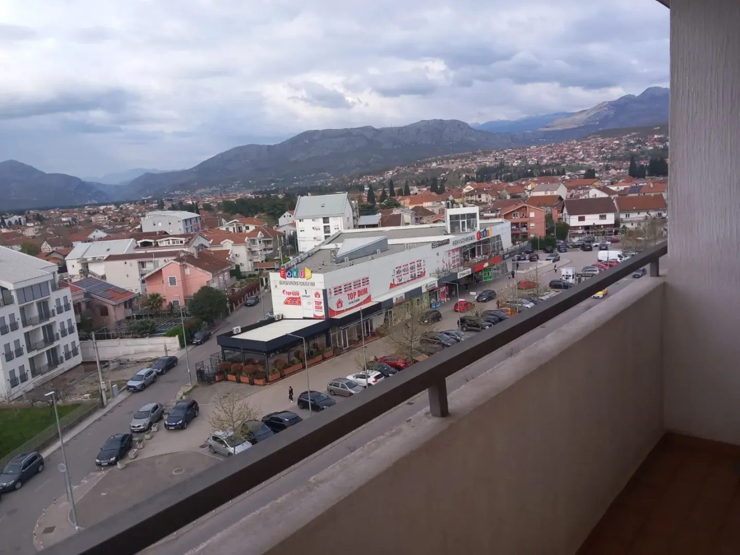 Pogled sa balkona na grad i planine u pozadini.