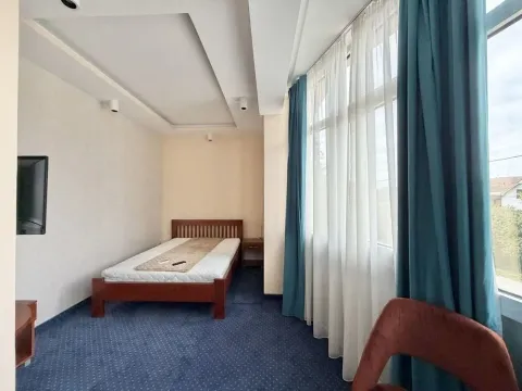 Spacious bedroom with a wooden bed and large windows. - image 4