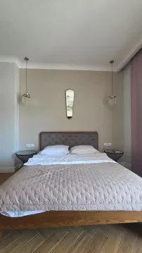 Uređena spavaća soba sa bračnim krevetom, noćnim stočićima i visećim lampama. - image 9