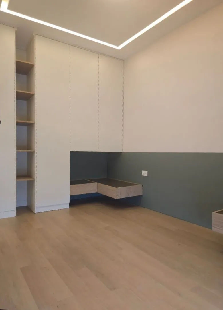 Prazna spavaća soba sa ugradnim plakarom i drvenim podom.