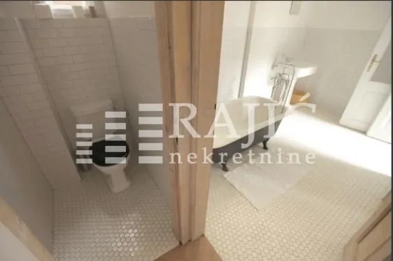 Spacious bathroom with a bathtub and a separate toilet area.