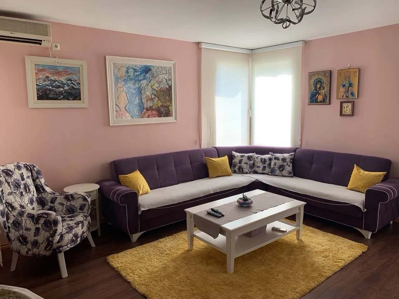 Dnevna soba sa ljubičastom ugaonom garniturom, foteljom i stolićem.