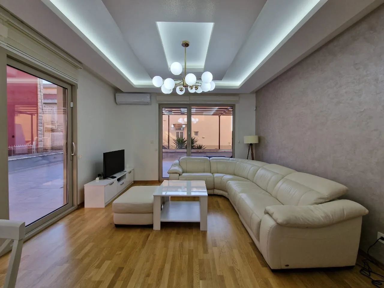 Spacious living room with a sectional sofa, TV unit, and access to the terrace.