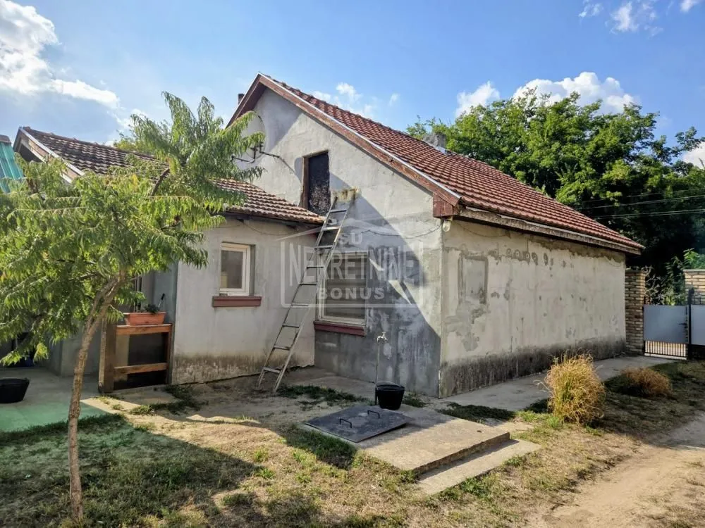 Pogled na dvorišnu stranu kuće sa fasadom u izgradnji i merdevinama.