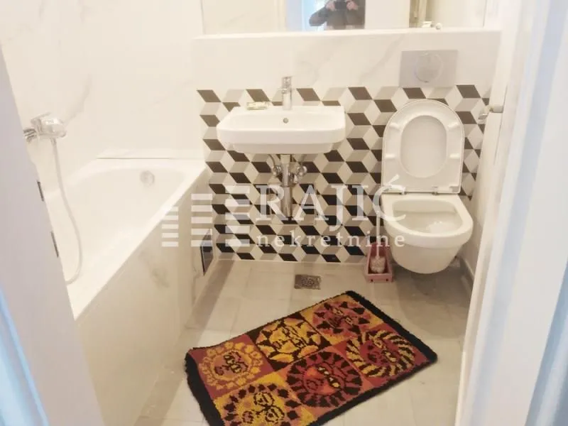 Modern bathroom with a bathtub, washbasin, and toilet.