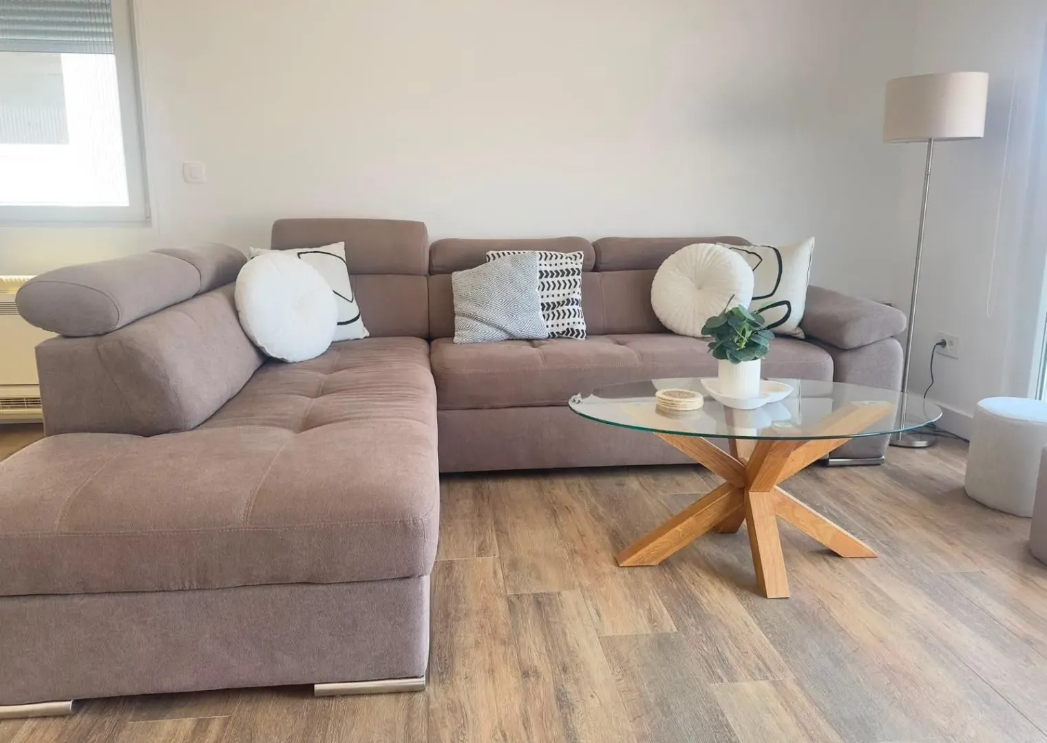 Bright living room with a sectional sofa and a glass coffee table.
