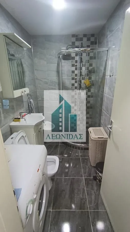 Small bathroom with a shower cabin, sink, and washing machine.