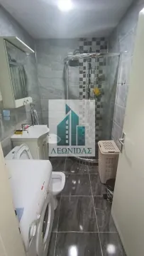 Small bathroom with a shower cabin, sink, and washing machine. - image 15