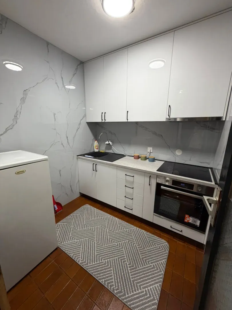 Small equipped kitchen with white cabinets and a built-in oven.