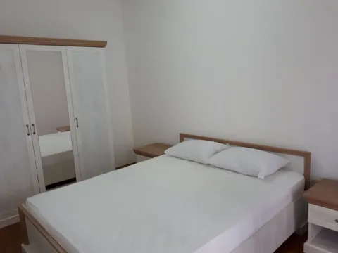 Svjetla spavaća soba sa bračnim krevetom, bijelim ormarom i noćnim stočićima. - image 7