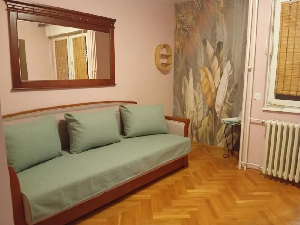 Living room with a sofa, hardwood flooring, and a decorative wall.
