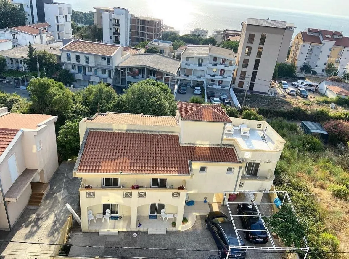 Pogled odozgo na trospratnu kuću sa terasama i parkingom blizu mora.