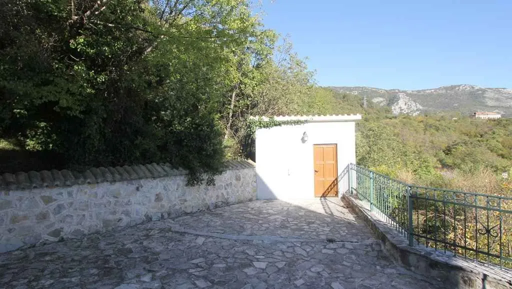 Mali pomoćni objekat sa popločanim dvorištem i ogradom.