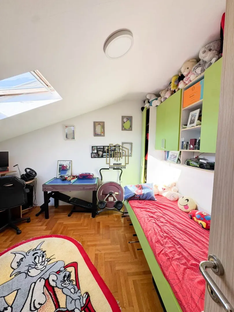 Dječija soba u potkrovlju sa krevetom, radnim stolom i krovnim prozorom.