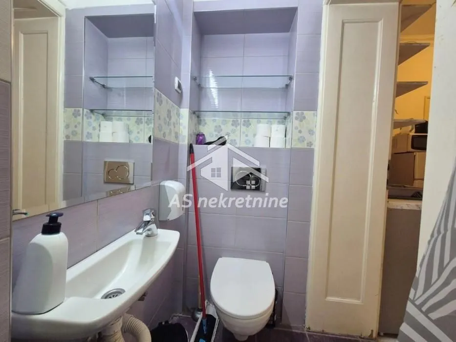 Small bathroom with a sink, toilet, and wall tiles.