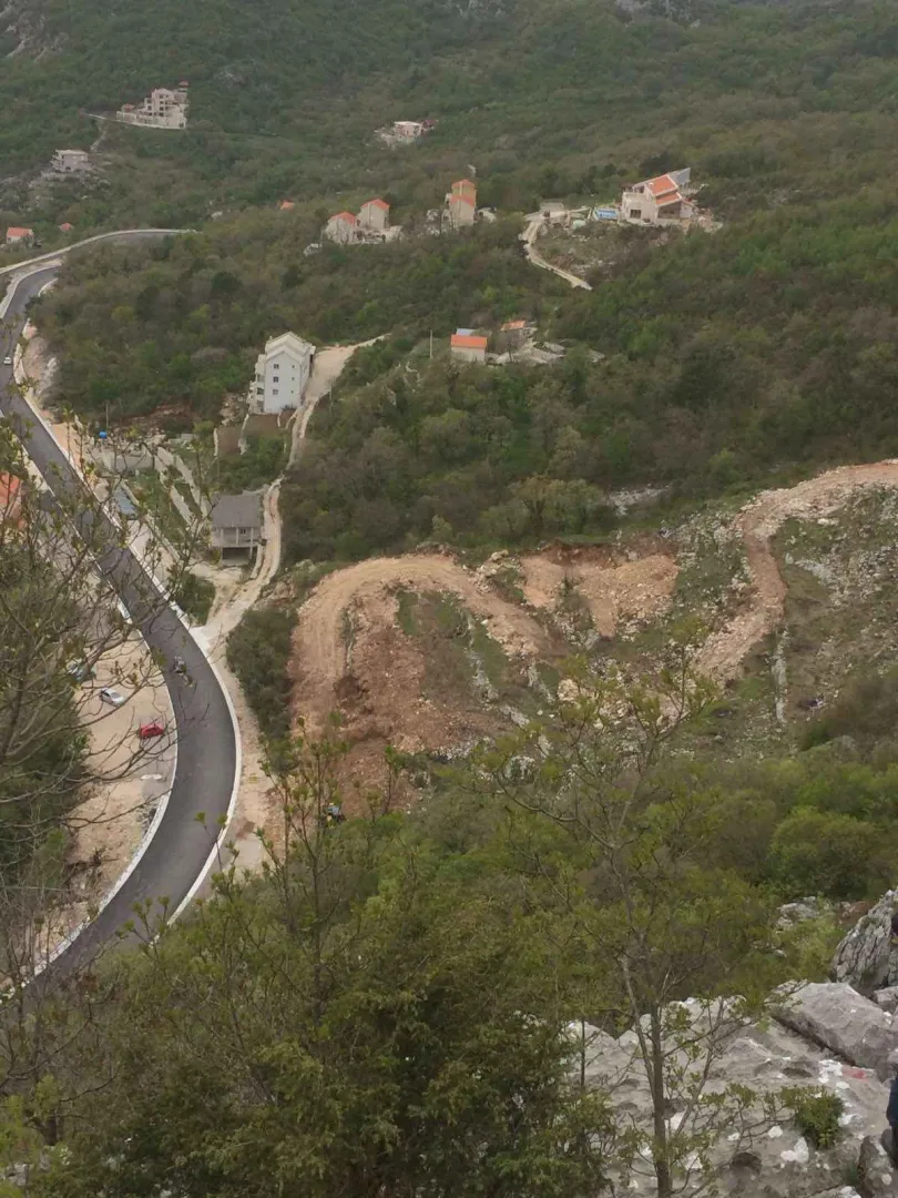 Pogled iz ptičje perspektive na okolni pejzaž sa putem i kućama.