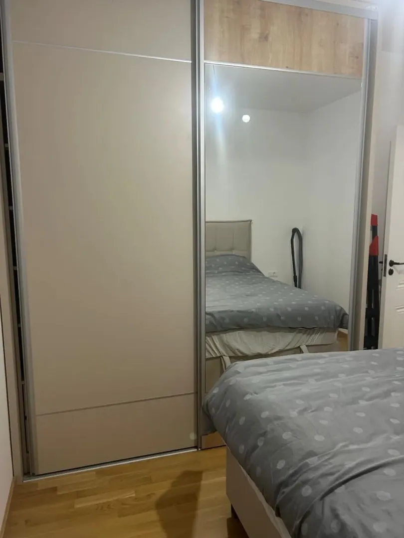 Bedroom with a bed and a large mirrored wardrobe.