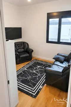 Small living room with black leather sofas and a wall-mounted TV. - image 3
