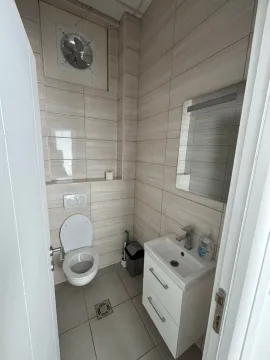 Smaller bathroom tiled with ceramic tiles featuring a sink and a toilet. - image 9