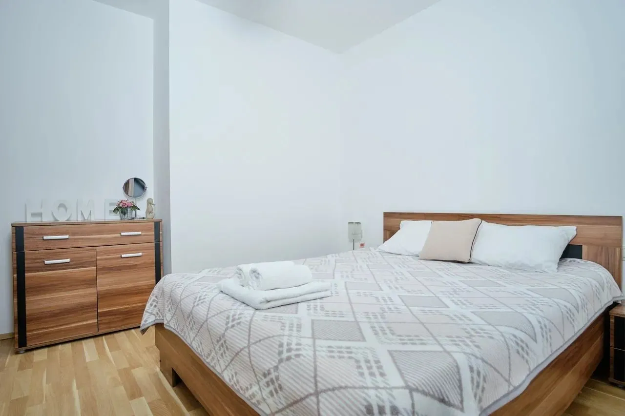 Bright bedroom with a double bed and a wooden dresser.