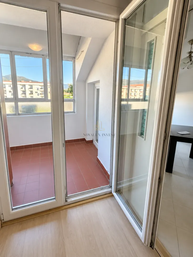 View through open balcony doors towards an enclosed terrace with ceramic tiles.