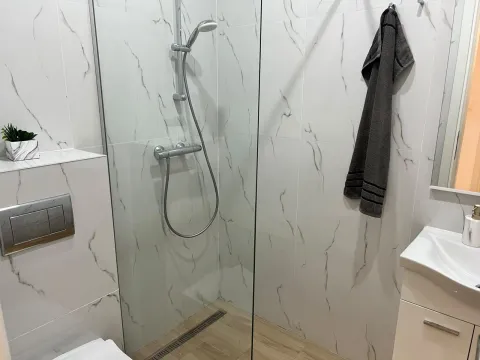 Savremeno opremljeno kupatilo sa tuš kabinom i bijelim keramičkim pločicama. - image 10