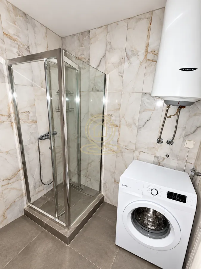 Bathroom equipped with a shower cabin, water heater, and washing machine.