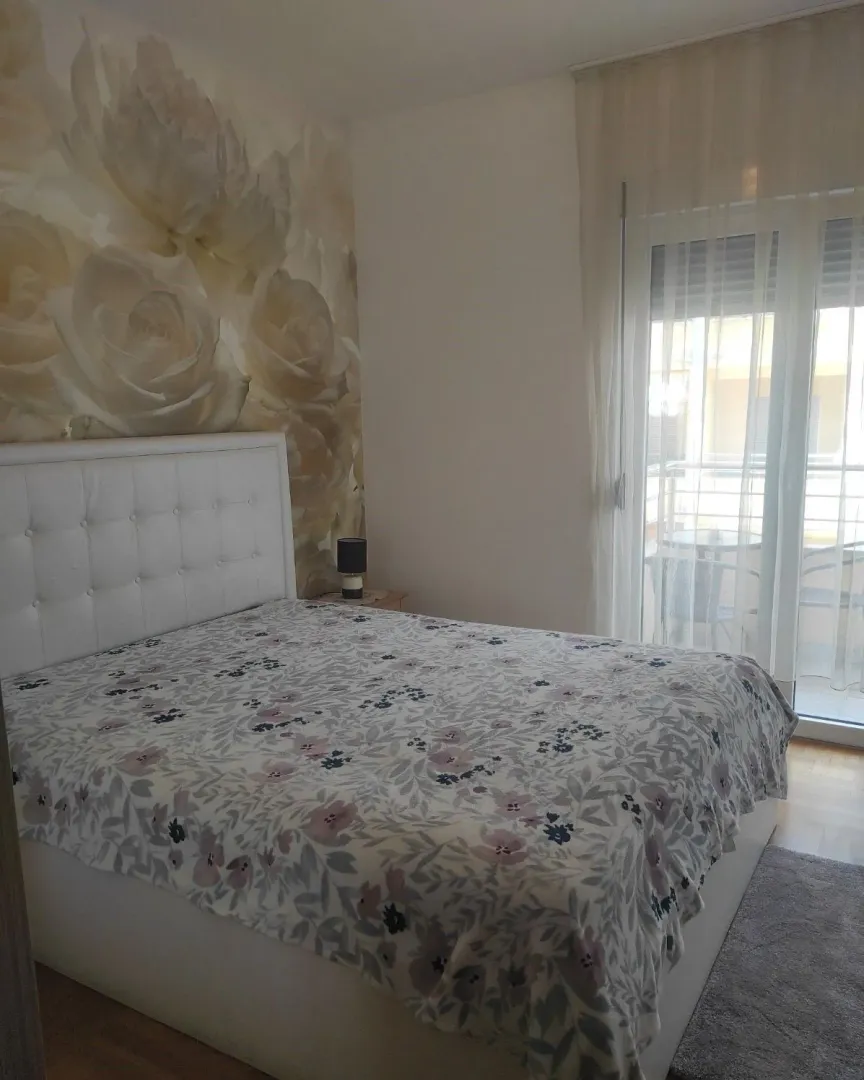 Furnished bedroom with a double bed and floral motif wallpaper.