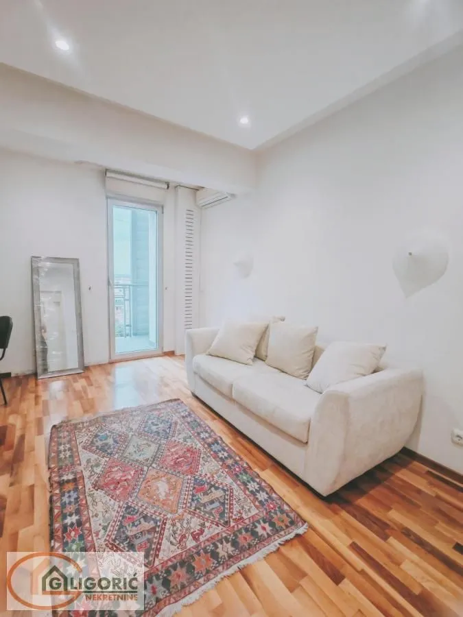 Living room with a beige sofa, colorful rug, and access to the terrace.