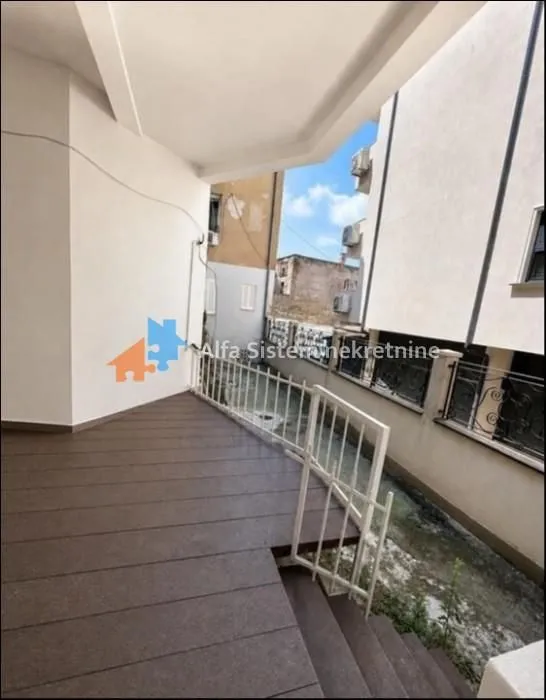 Covered terrace with wooden decking and a view of surrounding buildings.