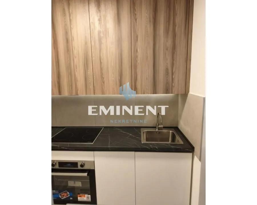 View of a part of the kitchen with a countertop, sink, built-in oven, and cabinets.