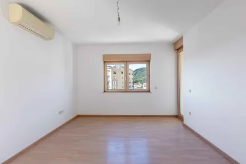 Prazna svijetla soba sa drvenim parketom, klima uređajem i prozorom koji gleda na okolne zgrade i brda. - image 7