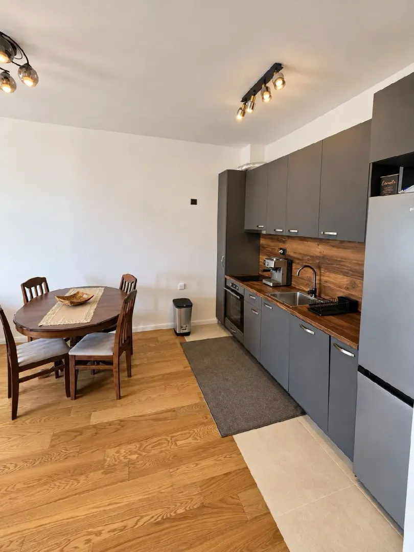 Modern kitchen with dark cabinets and a dining table with chairs.