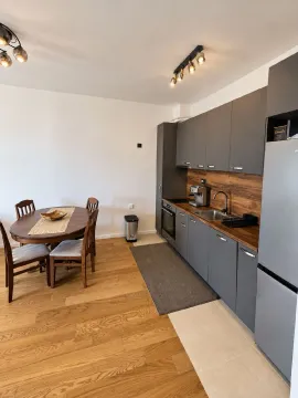Modern kitchen with dark cabinets and a dining table with chairs. - image 15