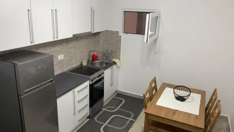 Compact white kitchen with a dining table and refrigerator. - image 4