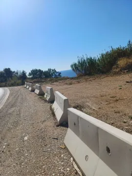Pogled na plac sa betonskim barijerama pored puta i pogledom na more. - image 11