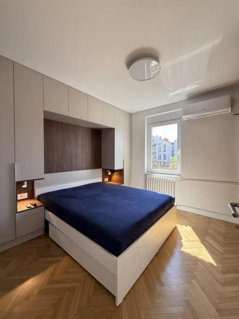 Modern bedroom with a double bed, fitted wardrobes, and wooden flooring.