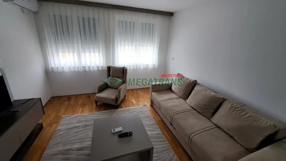 Dnevna soba sa garniturom, foteljom i stočićem.