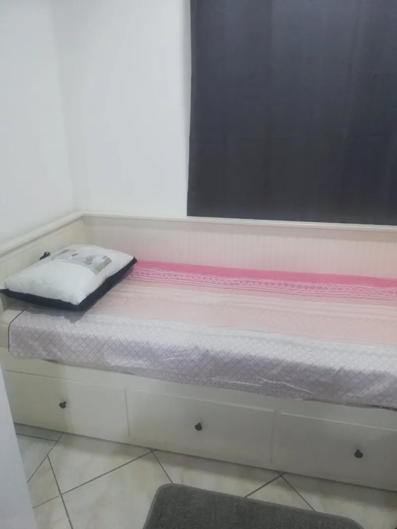 A simple bed with drawers in a bedroom.