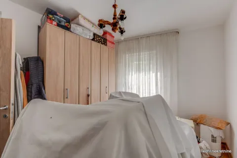 Spavaća soba sa velikim drvenim garderoberom i prekrivenim krevetom. - image 7