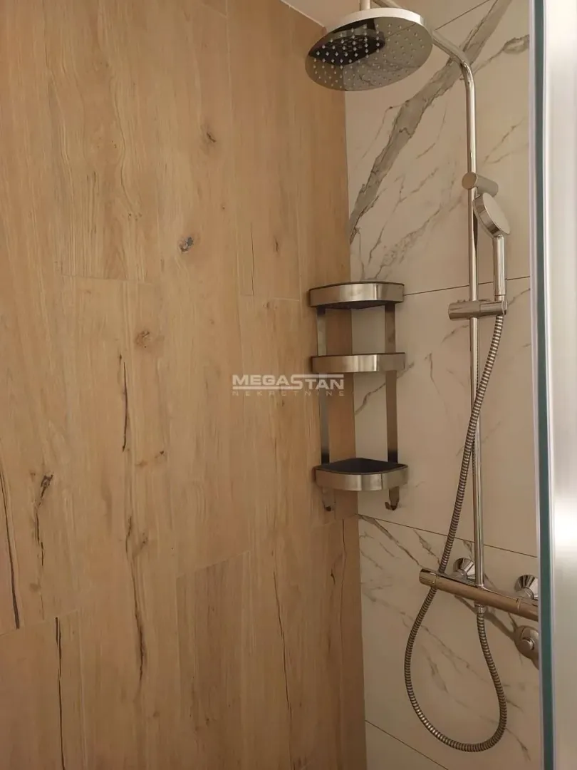 Moderna tuš kabina sa drvenim pločicama i mermernom pozadinom.