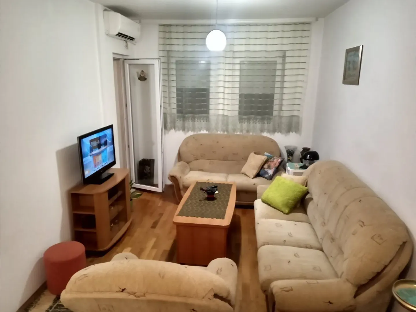 Dnevna soba sa garniturom za sjedenje, klub stolom i televizorom.