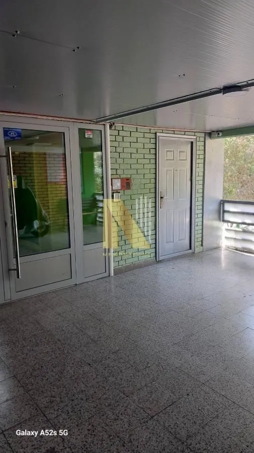 Building entrance with tiled floor and green wall cladding.